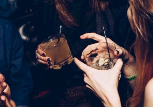 People are socializing, holding drinks, and appearing to be in a lively, happy setting.