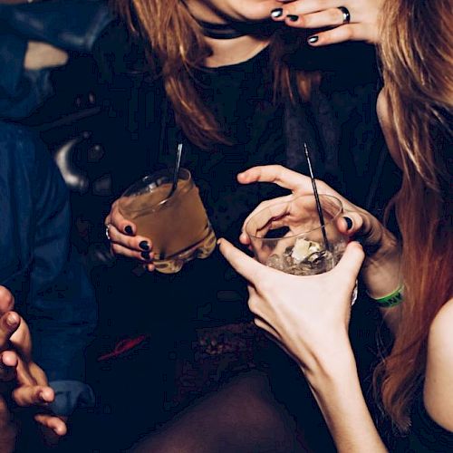 People are socializing, holding drinks, and appearing to be in a lively, happy setting.