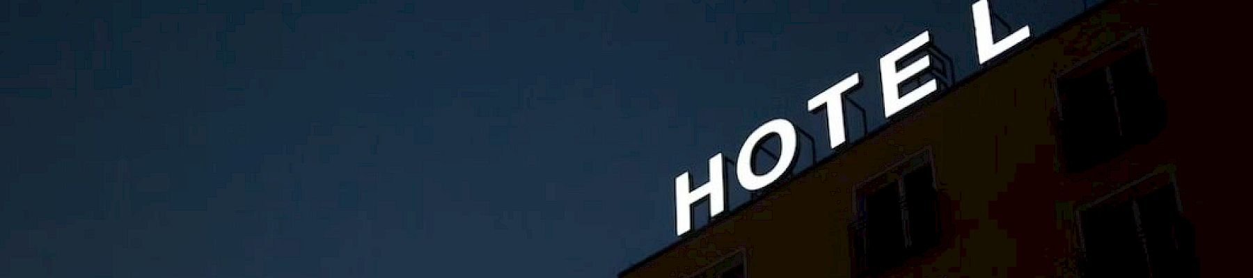 A building at night with the word "HOTEL" in illuminated letters on its top, but the letter "E" is unlit, making it appear as "HOT L."