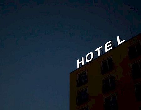 A building at night with the word "HOTEL" in illuminated letters on its top, but the letter "E" is unlit, making it appear as "HOT L."