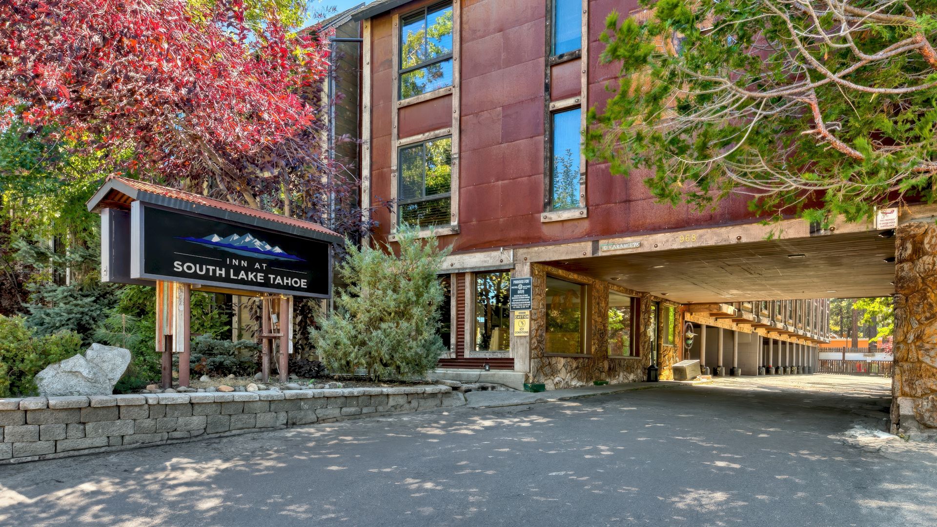 The image shows a rustic building in South Lake Tahoe with a signboard, surrounded by trees, and featuring a covered driveway.