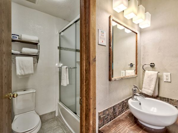 A clean bathroom with a shower, toilet, and sink area with a mirror and modern lighting above.
