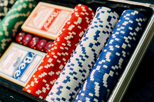 The image shows a poker set with green, red, and blue poker chips, two decks of cards, and red dice inside a case, ready for gameplay.