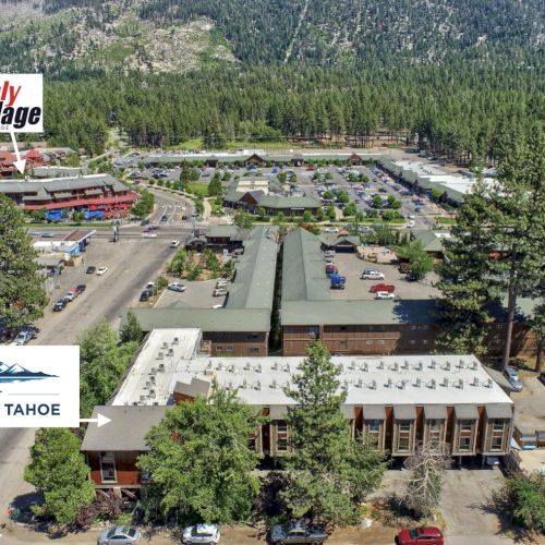 Aerial view of the Inn at South Lake Tahoe with the Shops at Heavenly Village nearby, surrounded by trees and mountains in the background.