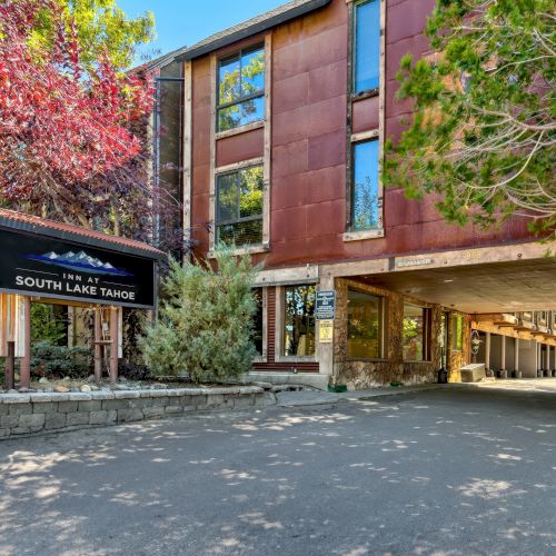 The image shows a building with a sign reading "South Lake Tahoe," surrounded by trees and a paved entrance area.