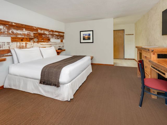 A hotel room with a bed, desk, and TV