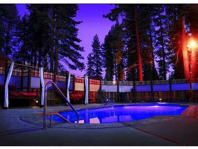 A swimming pool at dusk surrounded by trees and fencing.