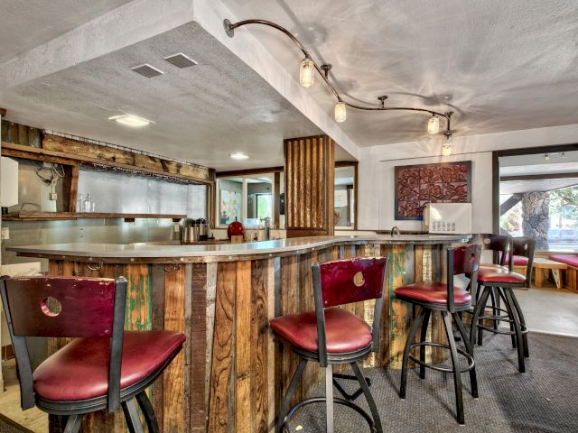 A bar with a wooden counter and red leather chairs