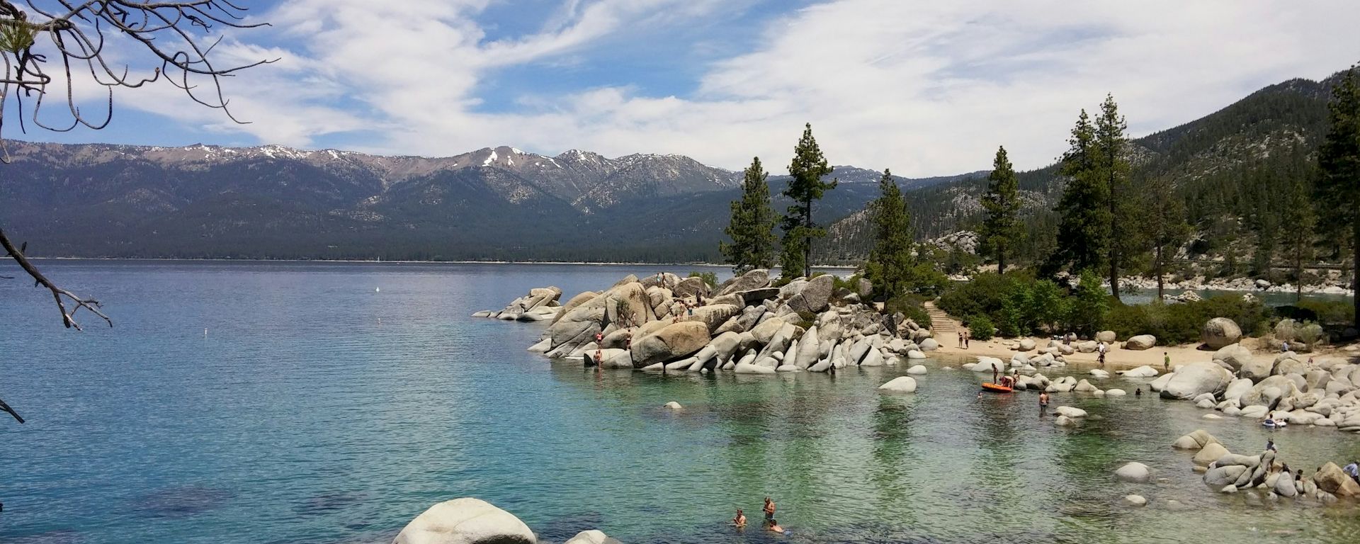 a lake with people in it and rocks and trees along the shore